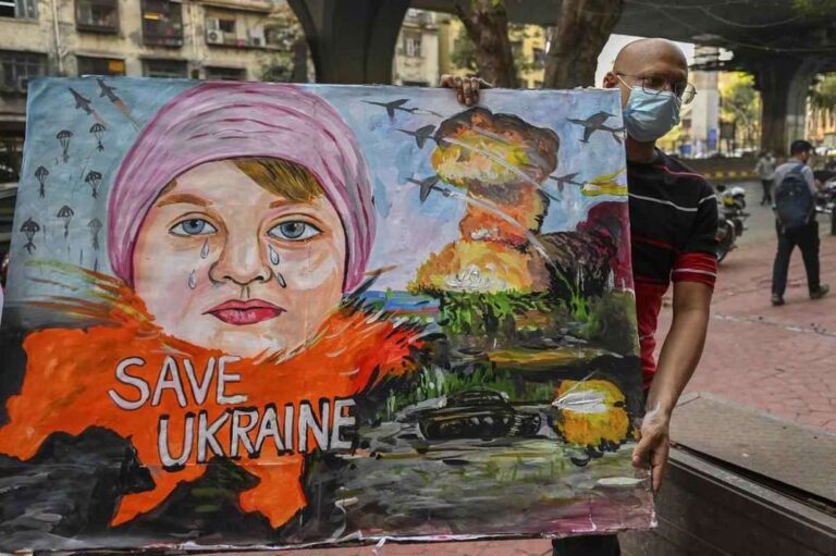 Um professor de arte carrega uma pintura para condenar a operação militar da Rússia na Ucrânia, em Mumbai, na Índia