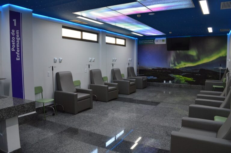 Foto do centro oncológico do HCN, com poltronas, painel decorado no teto e parede com foto da aurora boreal