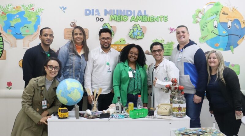 Imagem de colaboradores do Hospital Municipal da Brasilândia (HMB) participando do projeto "Salvei uma Orquídea", onde recebem mudas e aprendem sobre práticas sustentáveis.